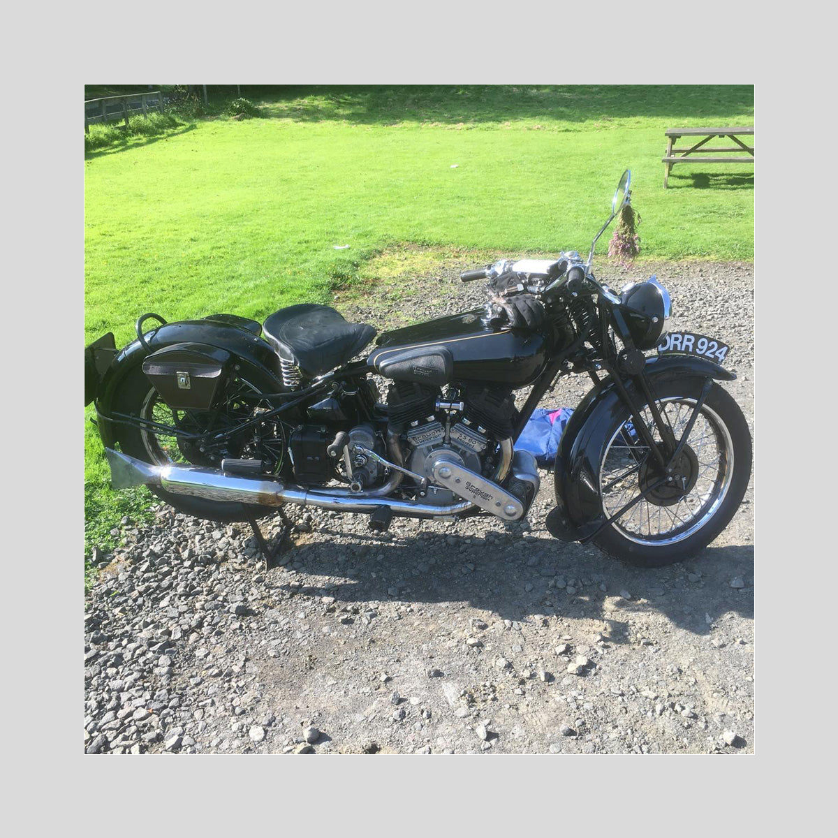 photograph of a 1937 Brough Superior SS80 motorcycle with a pair of worn riding gloves resting on the saddle. The reference photo used for the engraved artwork.