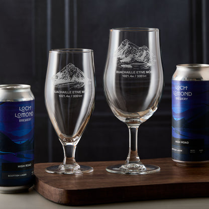Pair of stemmed beer glasses engraved with Buachaille Etive Mòr, photographed on a wooden board