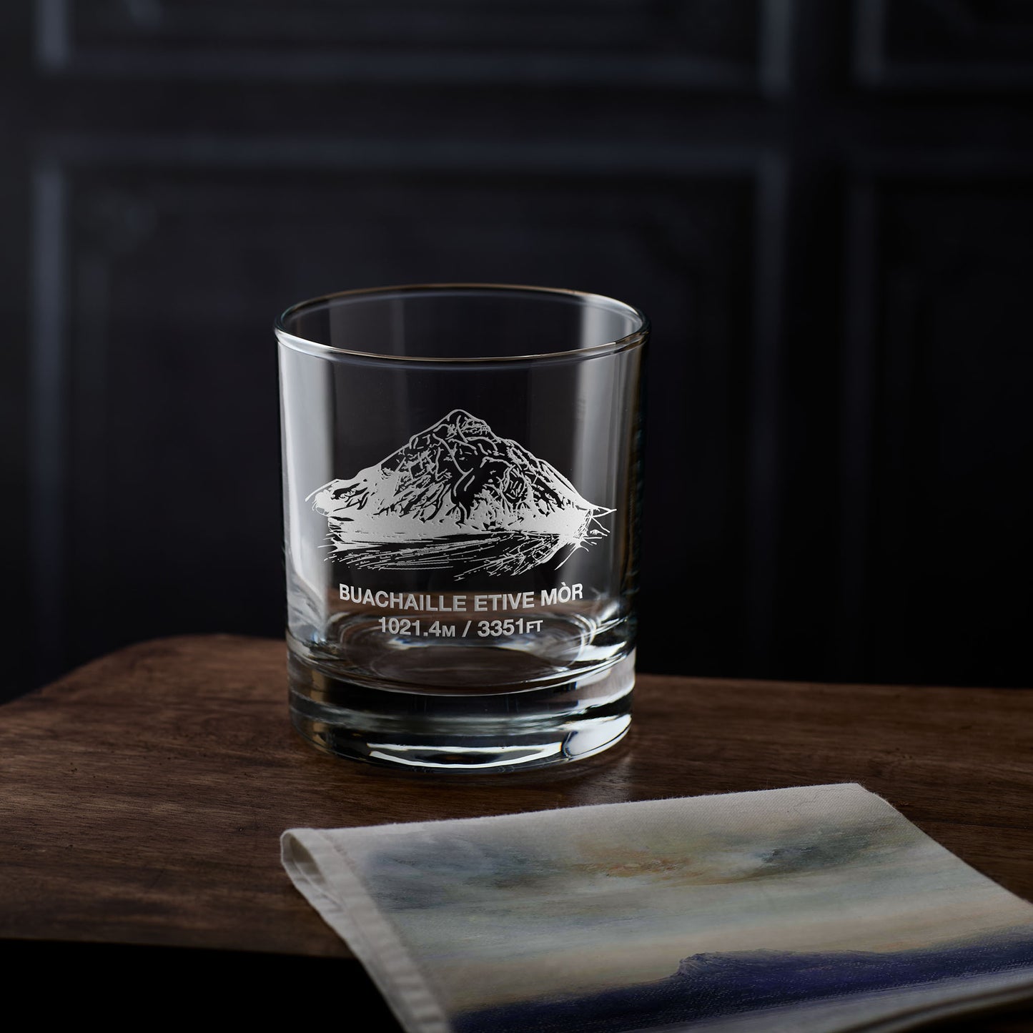 Whisky glass engraved with Buachaille Etive Mòr, photographed on a dark background