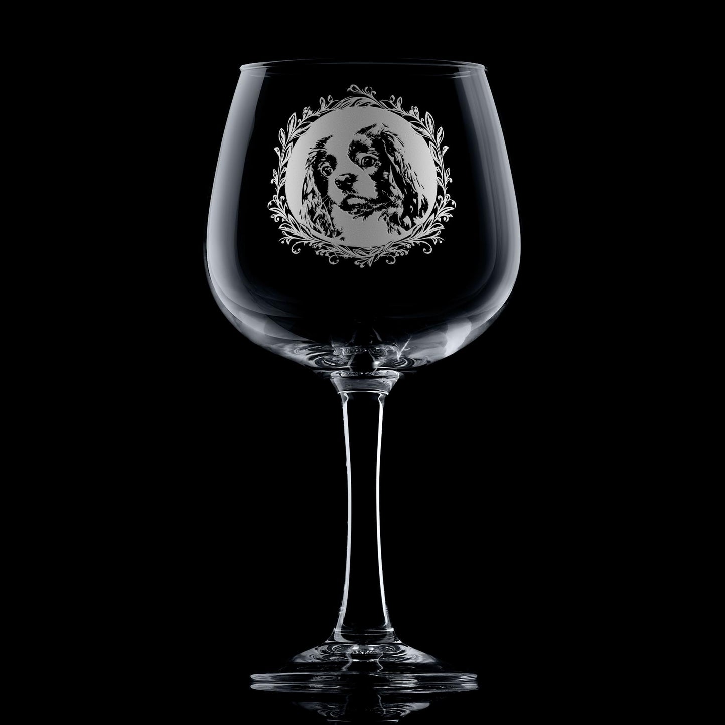 Hand-engraved Cavalier King Charles Spaniel gin glass displayed against dark background featuring a leafy garland dog portrait design by Just The Ticket.