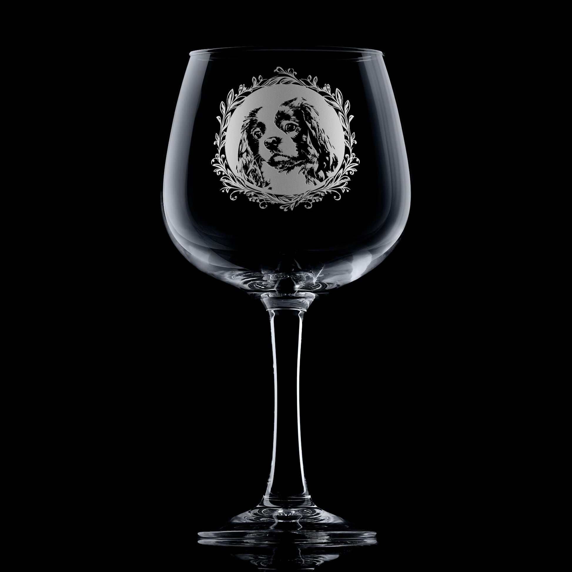 Hand-engraved Cavalier King Charles Spaniel gin glass displayed against dark background featuring a leafy garland dog portrait design by Just The Ticket.