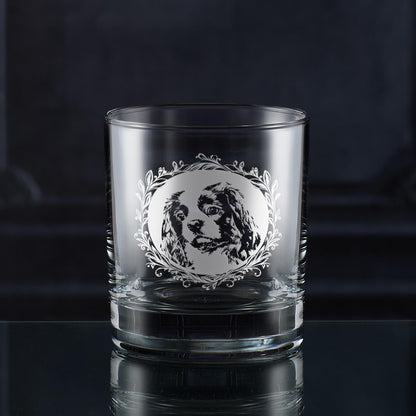 Hand-engraved Cavalier King Charles Spaniel whisky glass displayed against dark wood panelling, featuring leafy garland dog portrait design by Just The Ticket.