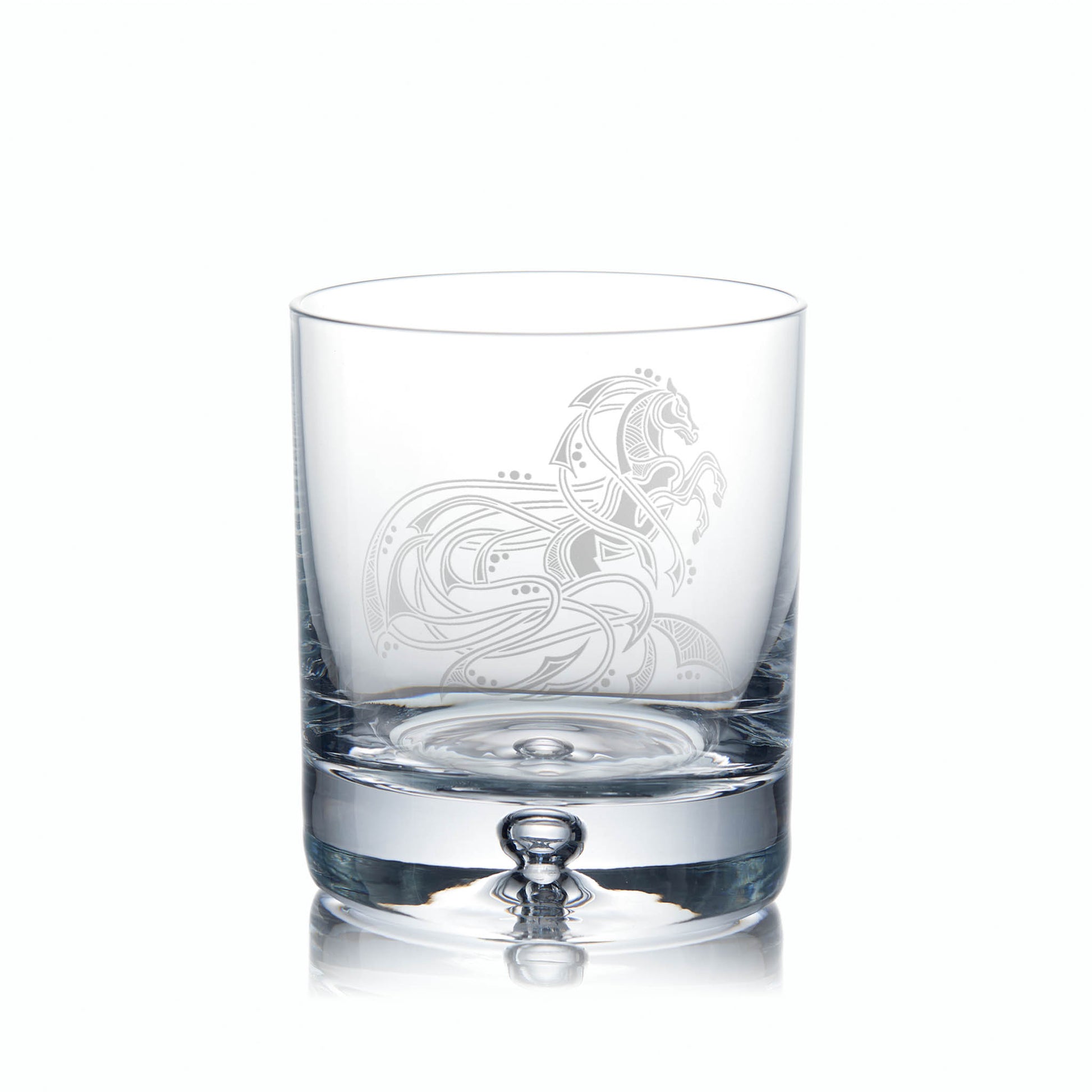 Clear glass tumbler with idelicate horse etching on a white background