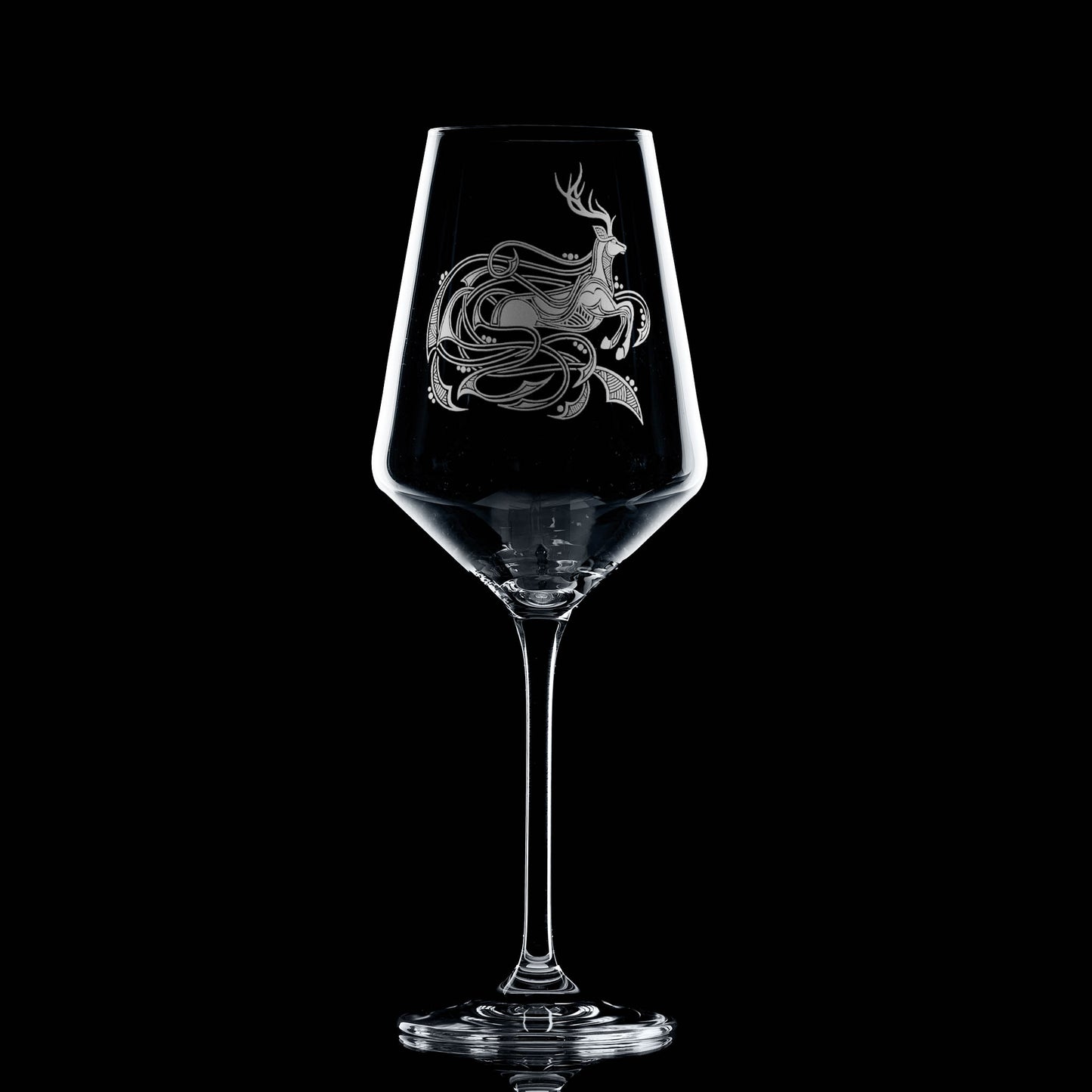 Clear wine glass with a engraved highland stag design on a black background