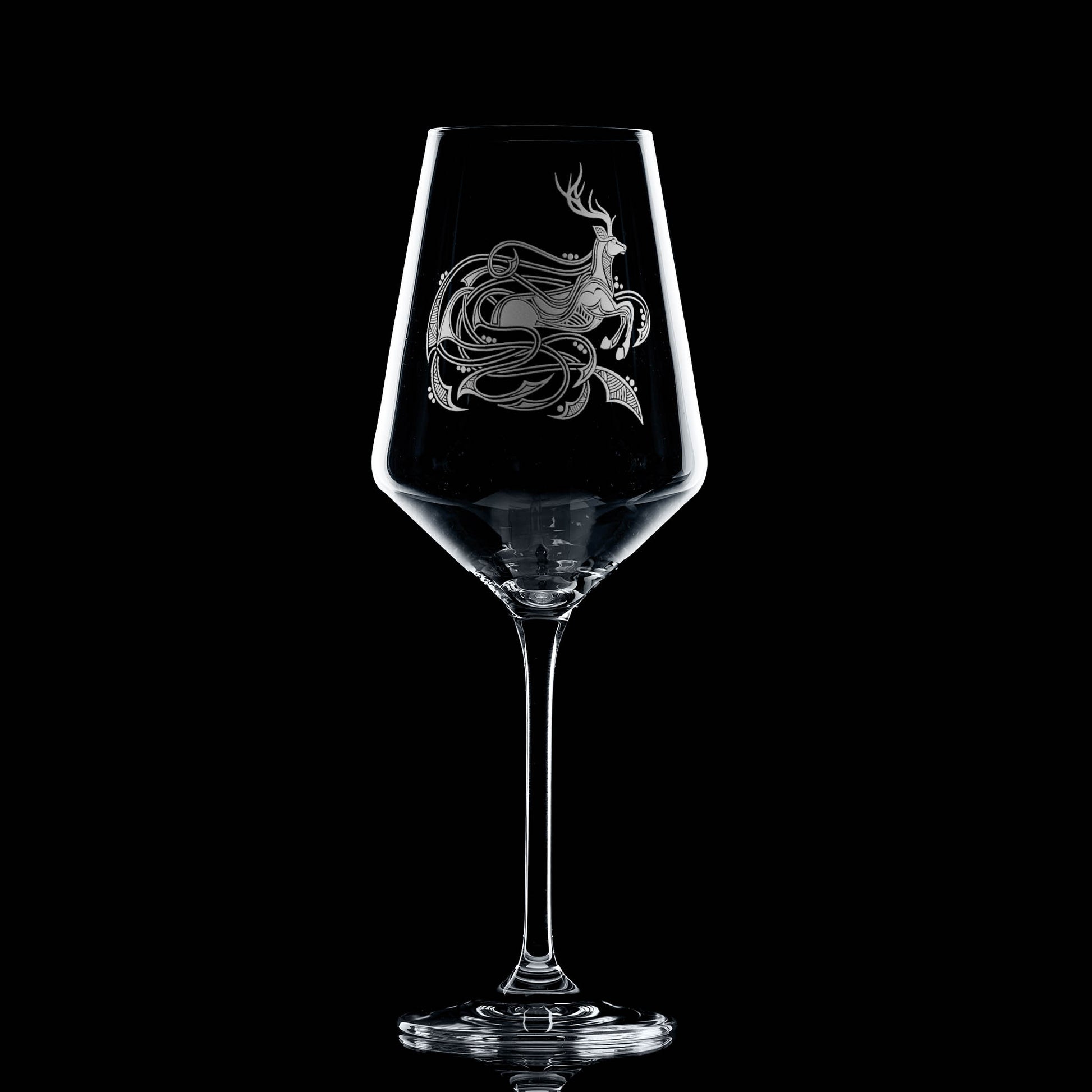 Clear wine glass with a engraved highland stag design on a black background