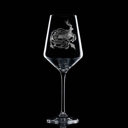 Clear wine glass with a engraved highland stag design on a black background