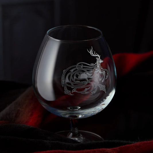 Brandy glass engraved with a stag surrounded by celtic knotwork on a dark background