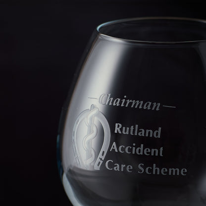 Close up of sandblast engraving on a brandy glass with engraved text and business logo on a black background