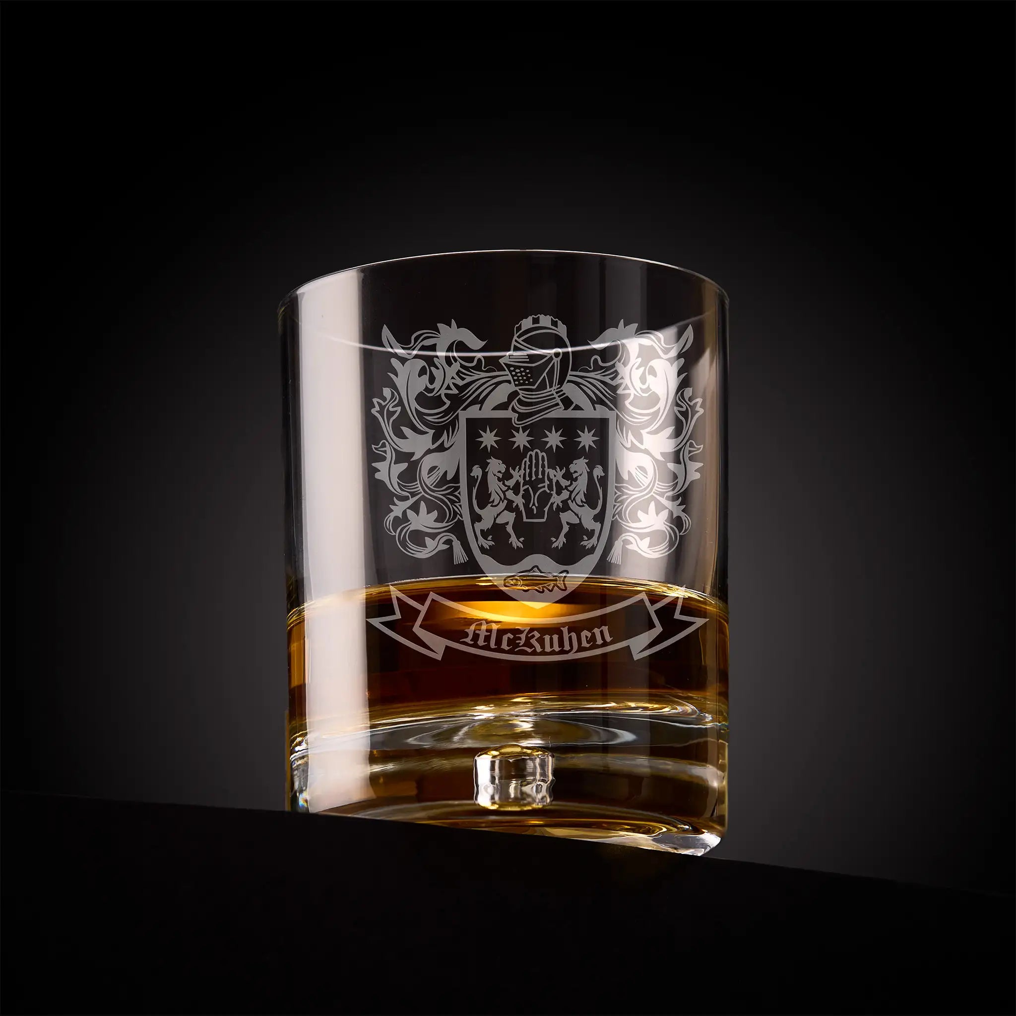 Heraldic whiskey glass with an engraved family crest on a dark background