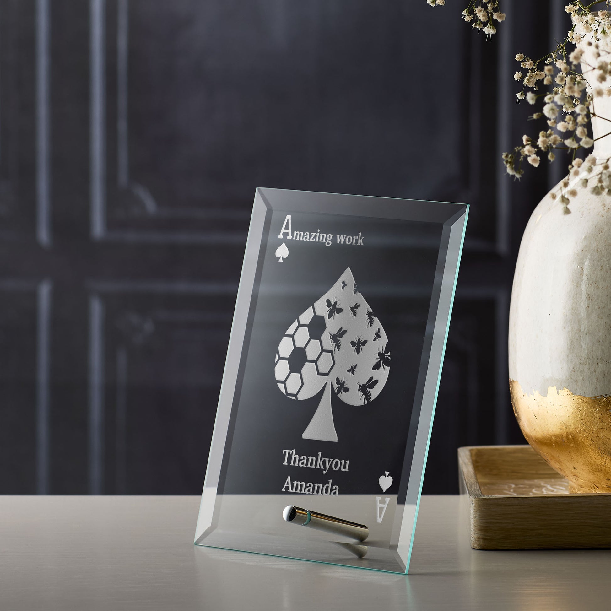 Corporate glass award plaque with engraved design and text on a table