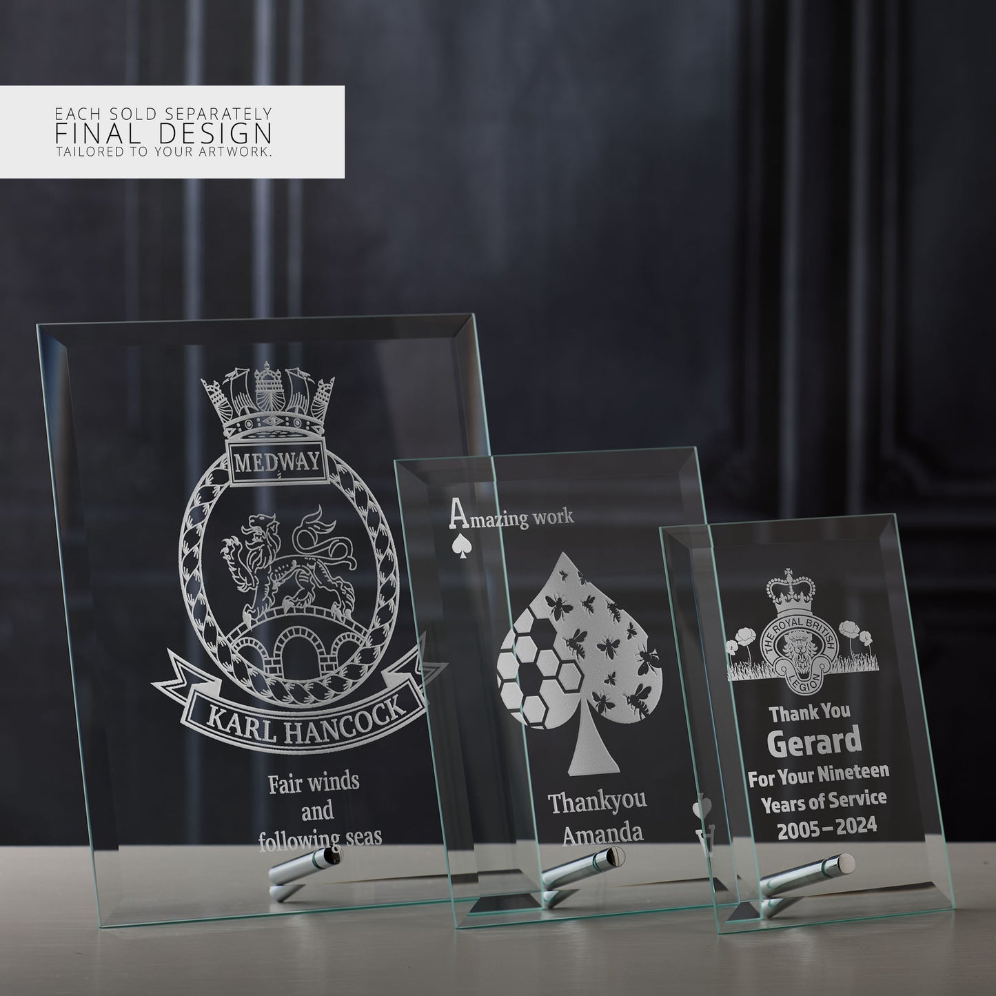 Three engraved glass display plaques with different custom designs on a dark background