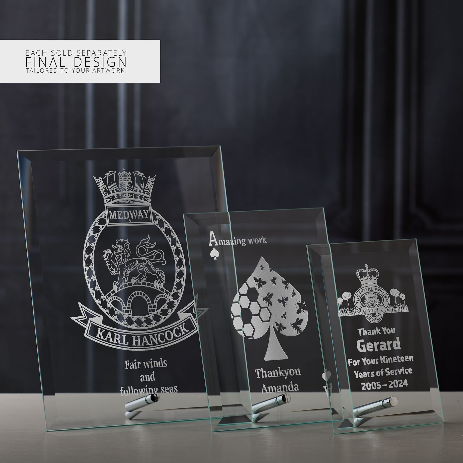 Three engraved glass display plaques with different custom designs on a dark background