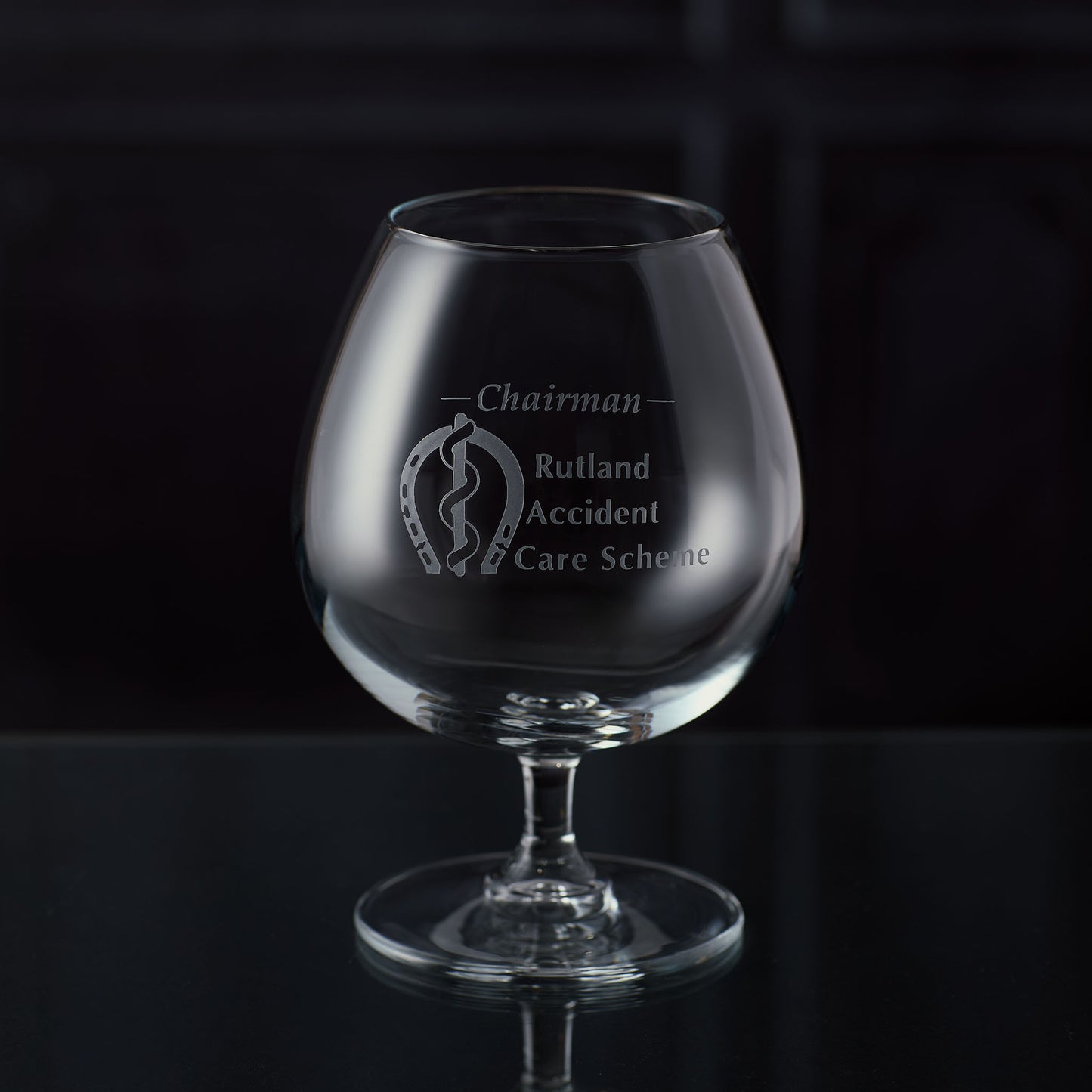 Brandy glass with an engraved corporate logo and personalised text on a dark background