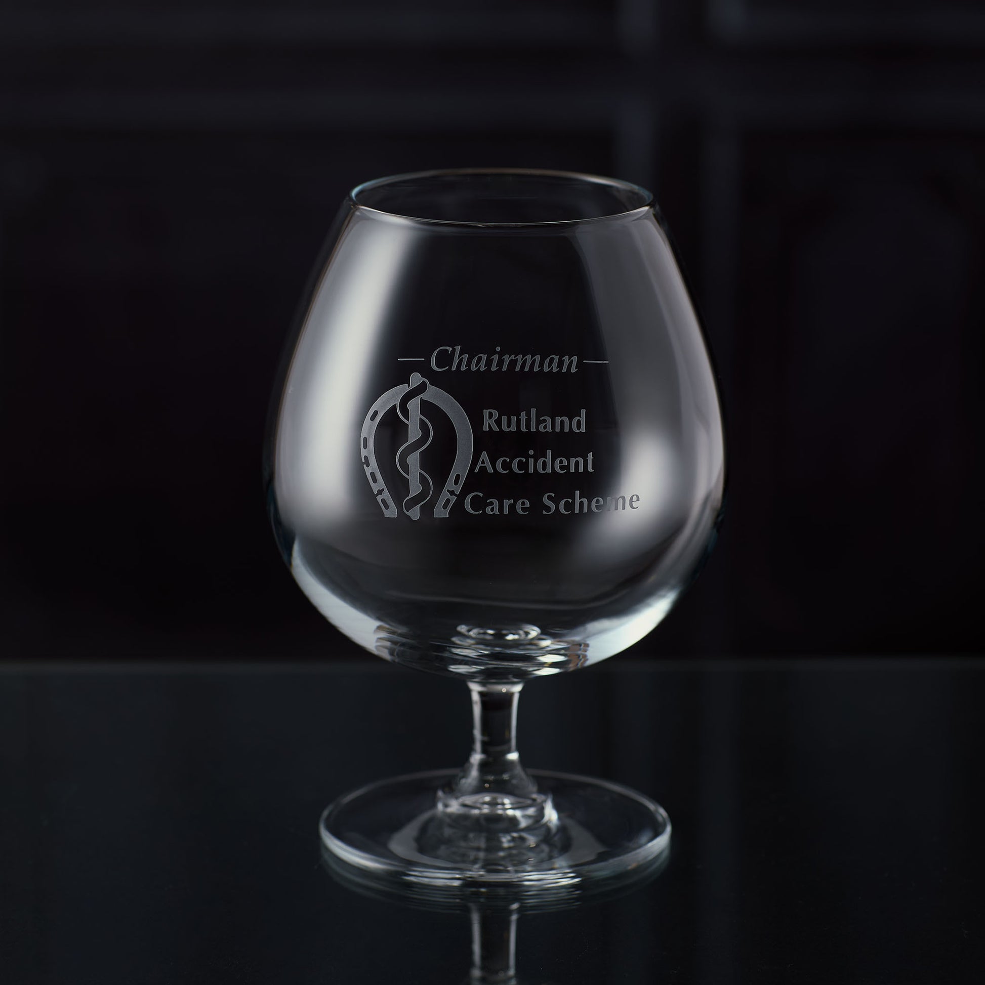 Brandy glass with an engraved corporate logo and personalised text on a dark background