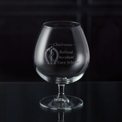 Brandy glass with an engraved corporate logo and personalised text on a dark background