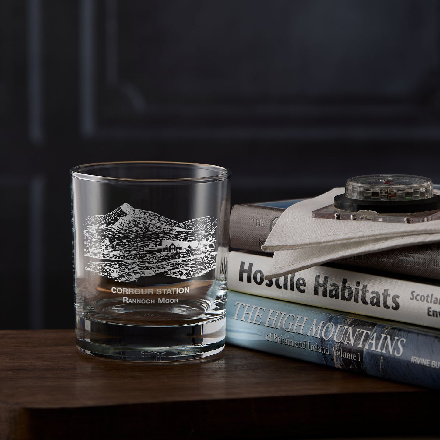 Rannoch Moor whisky glass with engraved design of Corrour railway station on a stack of books