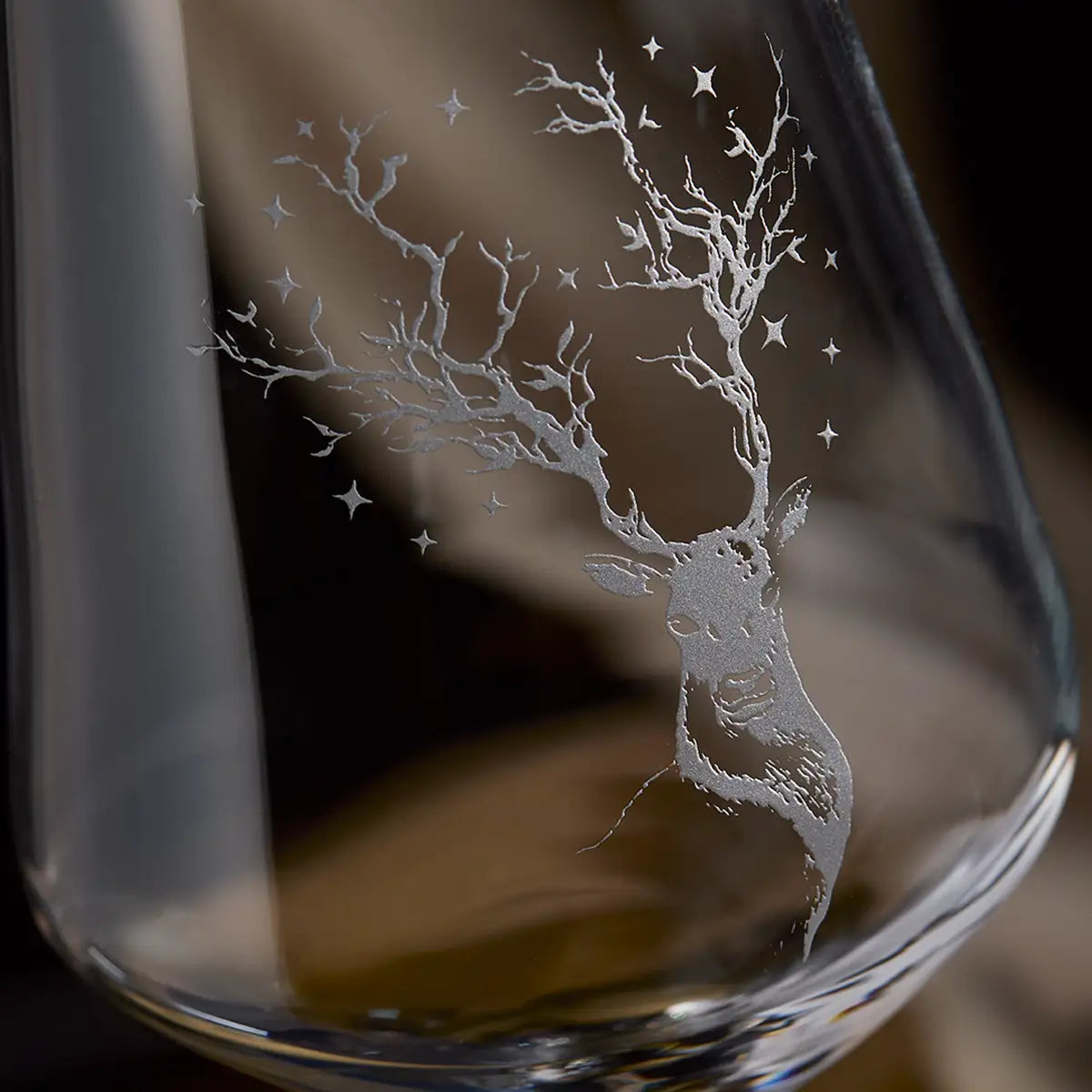 Glass with an engraved deer design on a dark background
