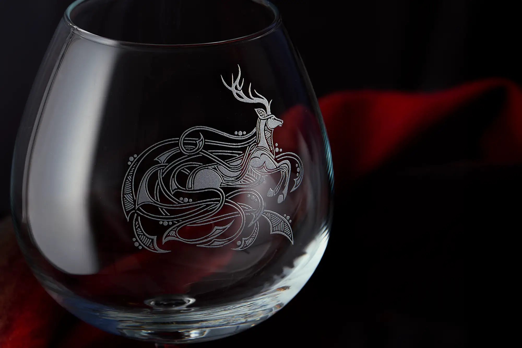 Glass with intricate deer design on a dark background