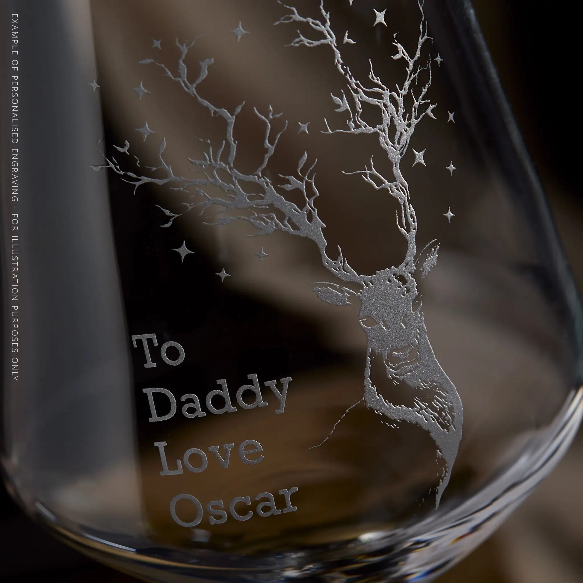 Engraving detail of a wine glass with deer design and personalised engraved text on a dark background