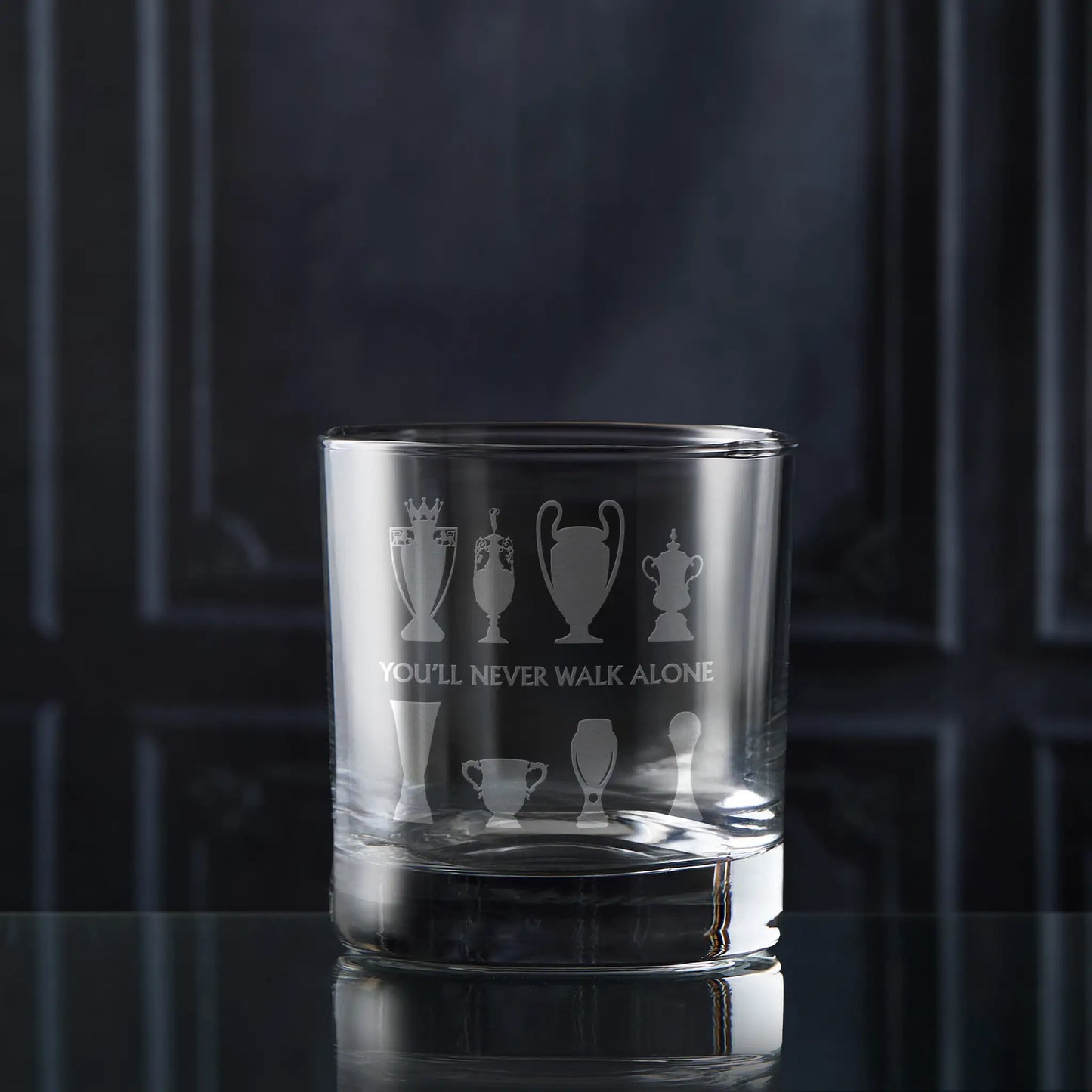 Whisky Glass with eight football trophy sillhouettes on a dark background