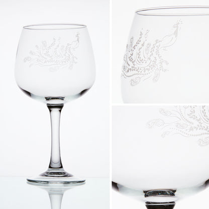 Detail-view of engraved gin glass featuring a flowing peacock tail with feathers and trailing leaves.