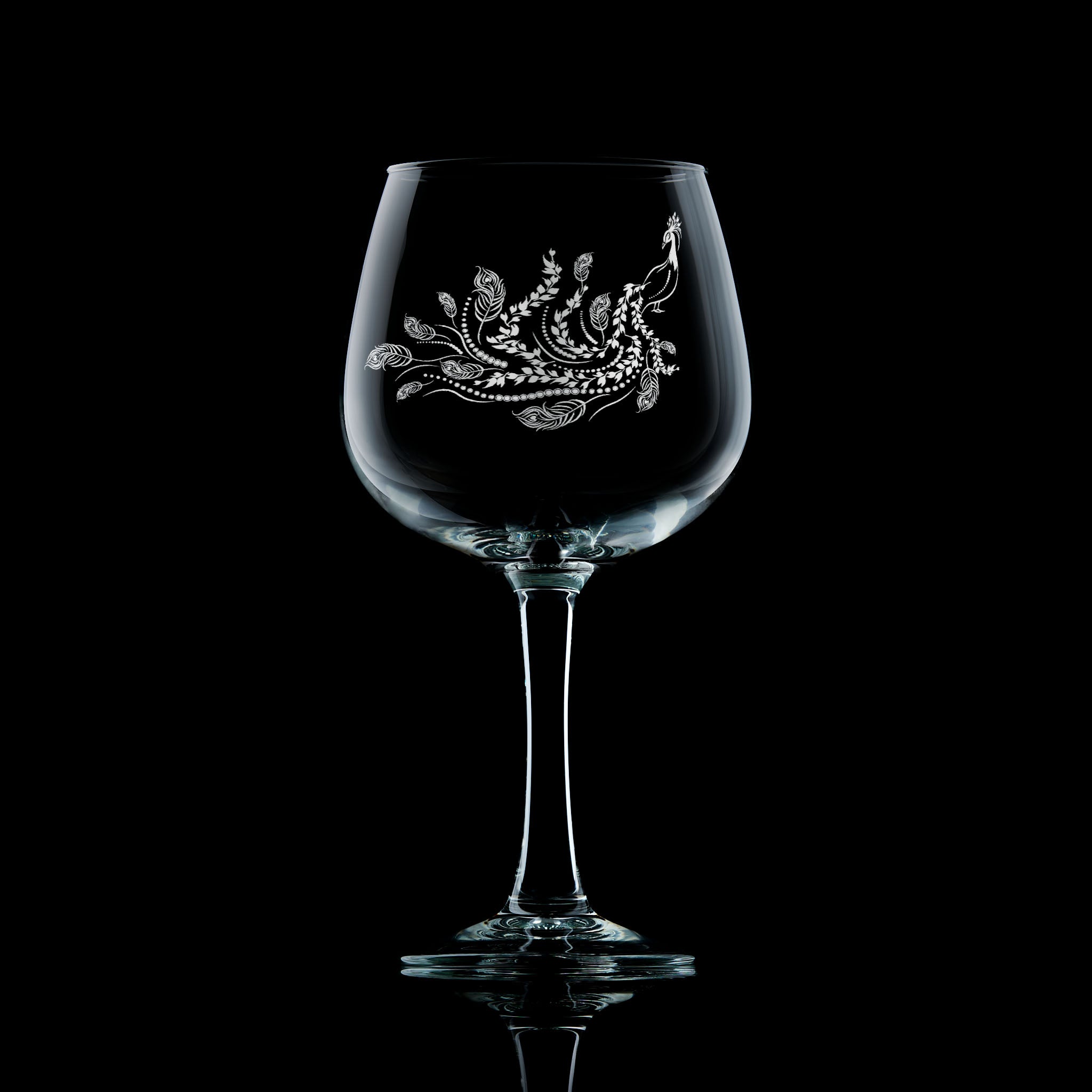 Engraved peacock stemmed gin glass etched with a flowing feathered tail and flora inspired by Pittencreiff park