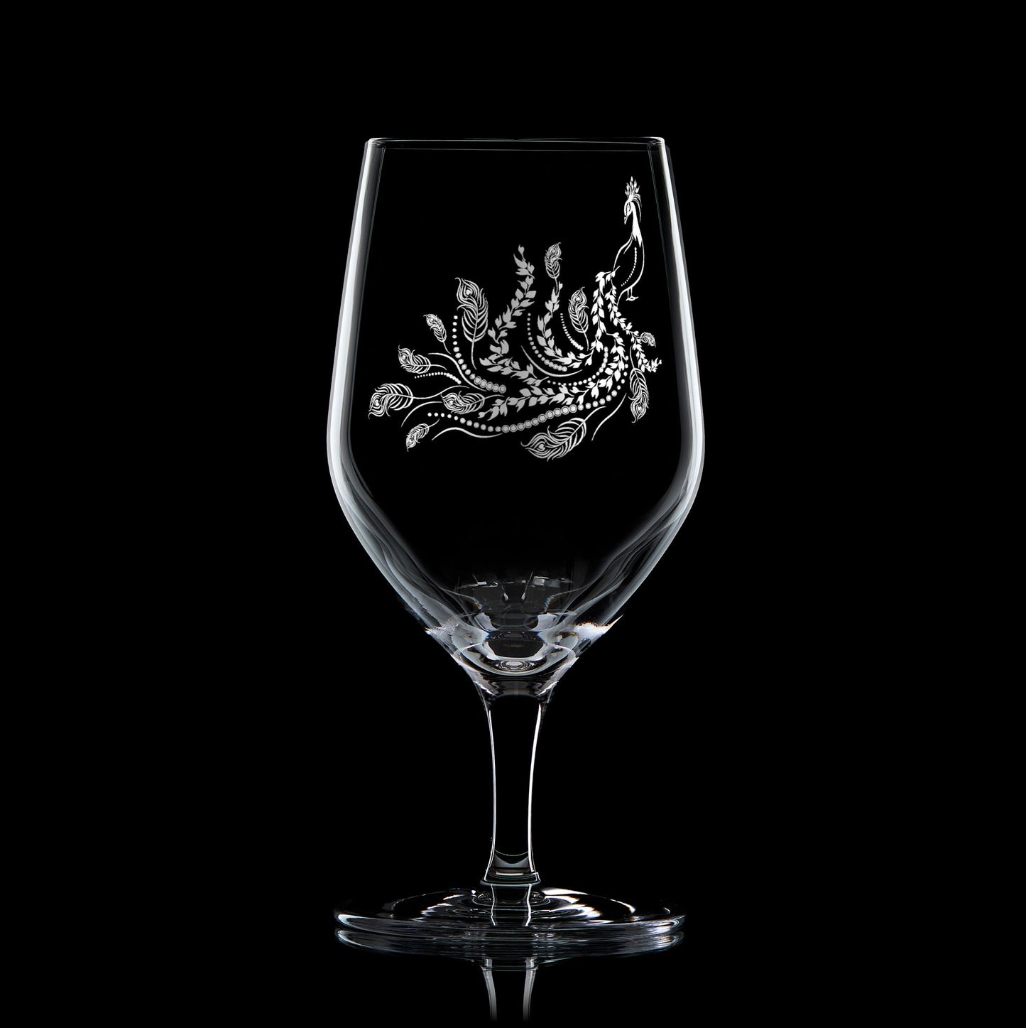 Engraved mineral water glass featuring peacock design with trailing feathers, shown on a black background