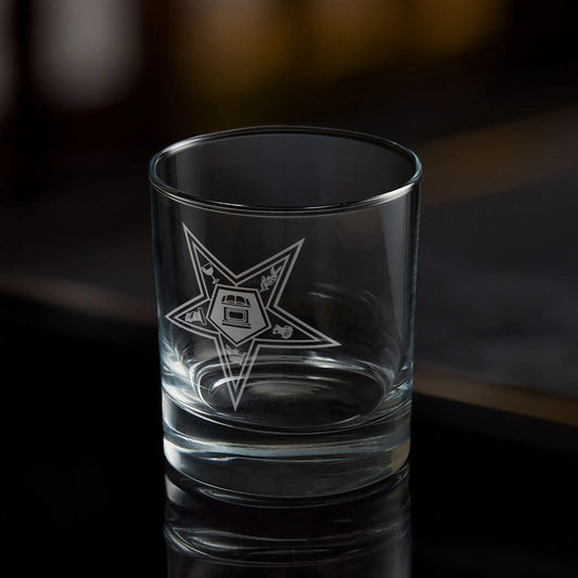 Clear whisky glass with engraved Order of the Eastern Star design on a dark background