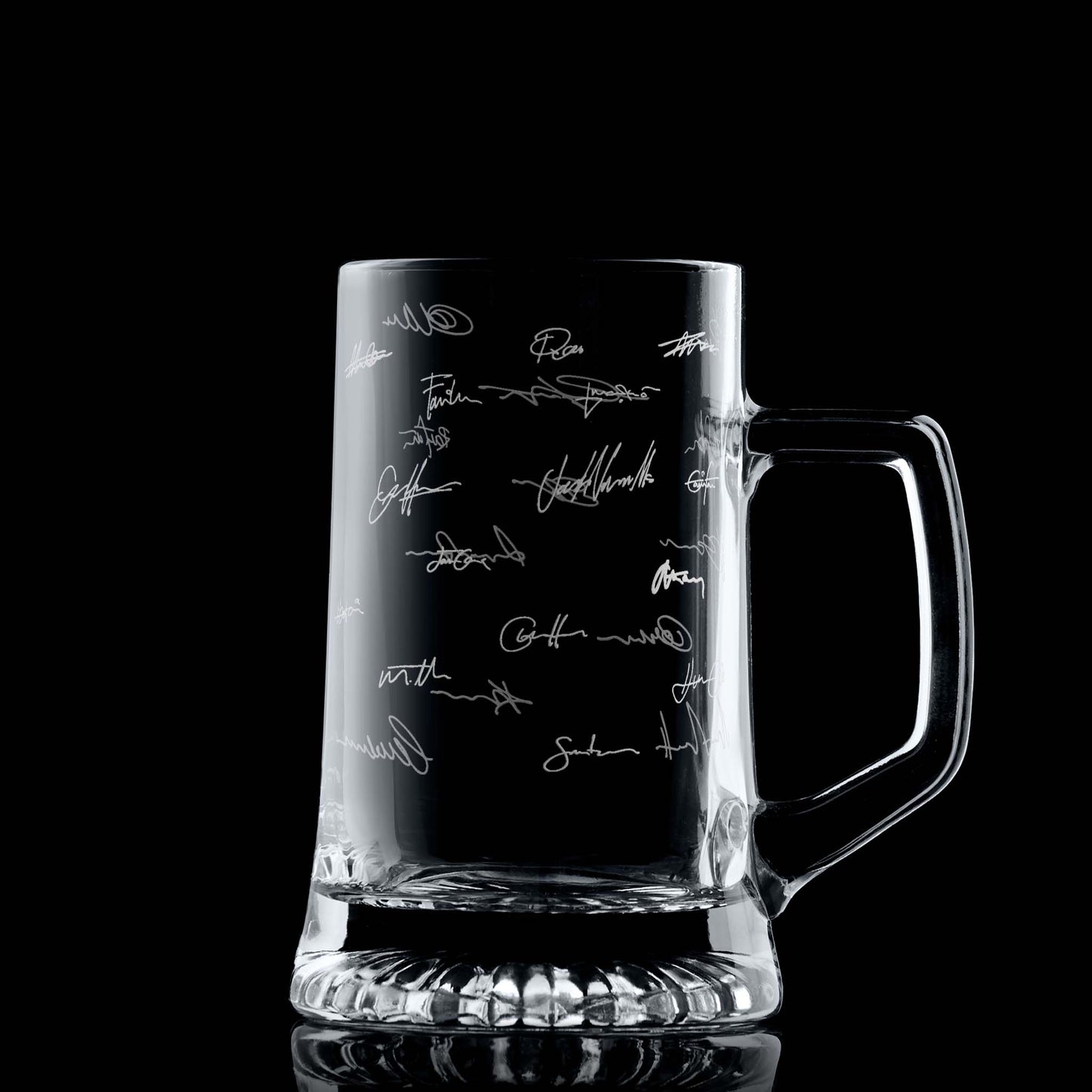 Glass beer tankard with engraved handwritten signatures on a black background