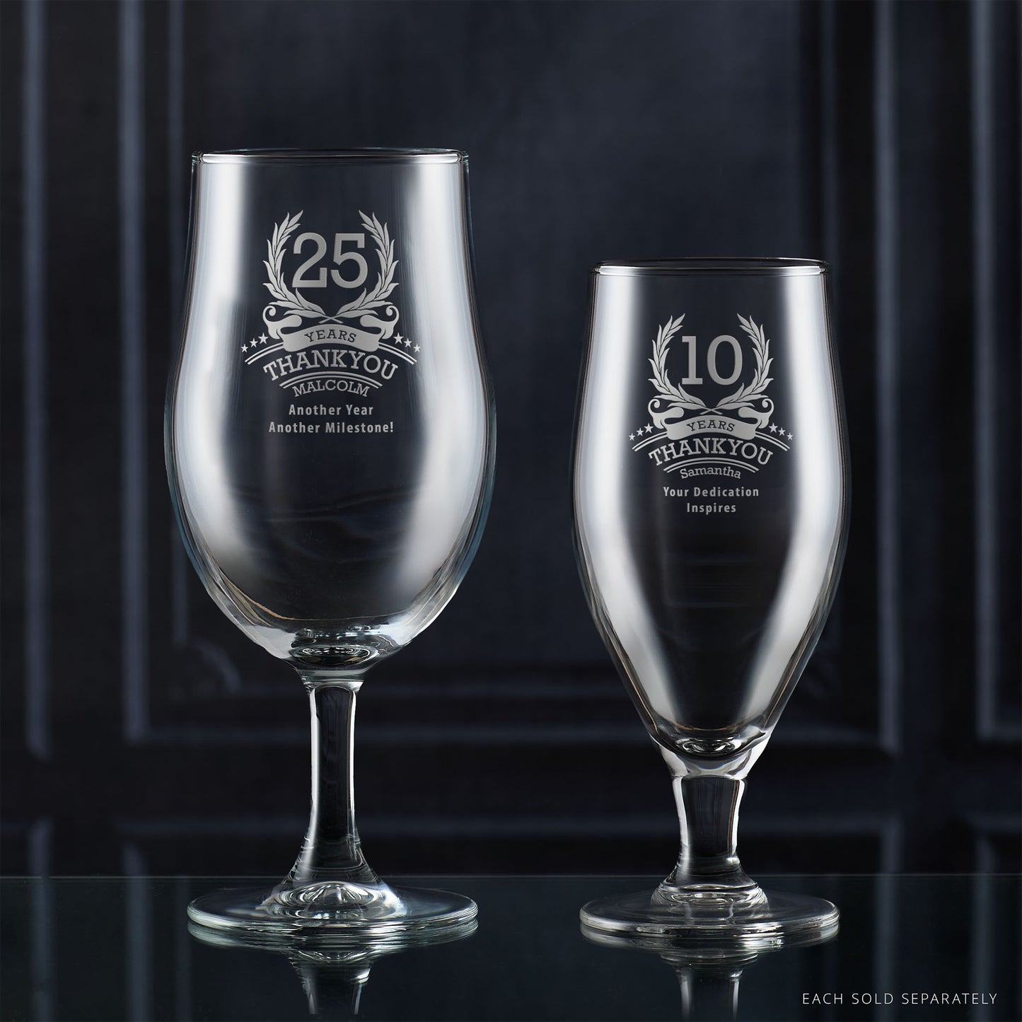 Two engraved corporate recognition glassware items on a reflective surface with a dark background