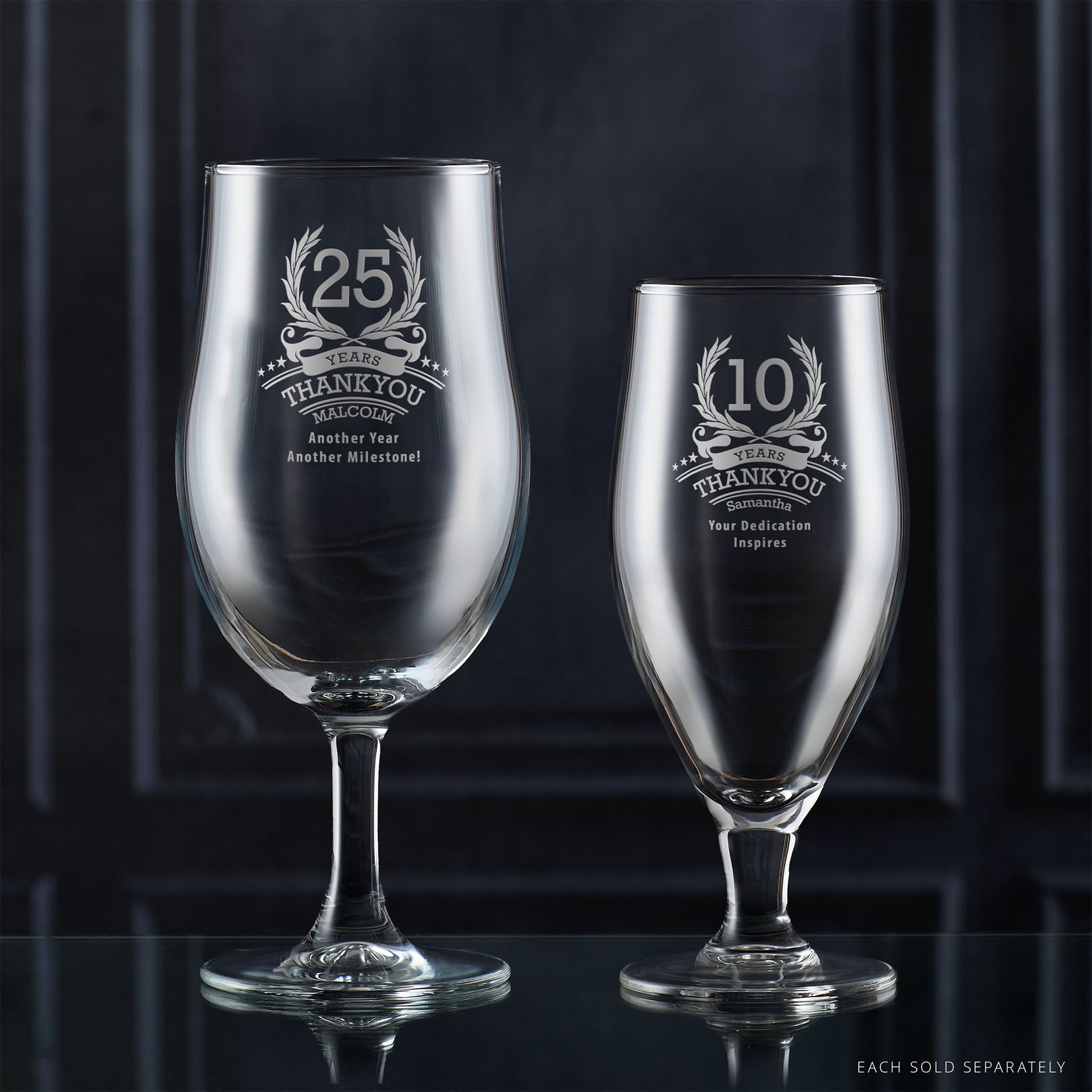 Two engraved corporate recognition glassware items on a reflective surface with a dark background