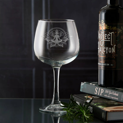 Engraved gin glass featuring Sukhasana yoga pose within a lotus flower, concentric mandala circles and dotted diamond pattern