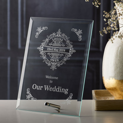 Personalized glass wedding sign with decorative text on a dark background