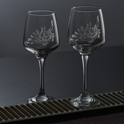 Two wine glasses each featuring a single engraved peafowl with a flowing tail of feathers and trailing leaves, inspired by Pittencrieff Park’s peacocks