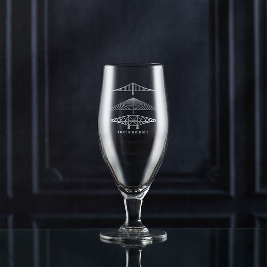 Stemmed beer glass with engraved scottish bridge design on a dark background
