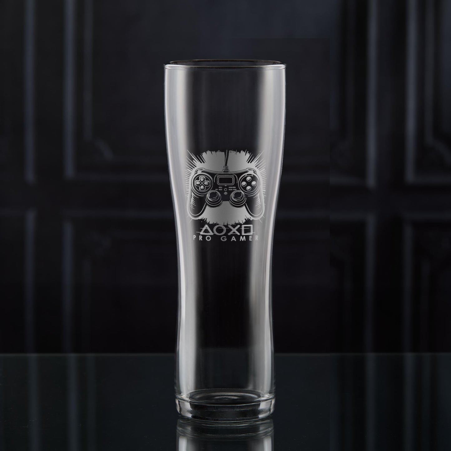 Pint glass with engraved games controller design on a dark background