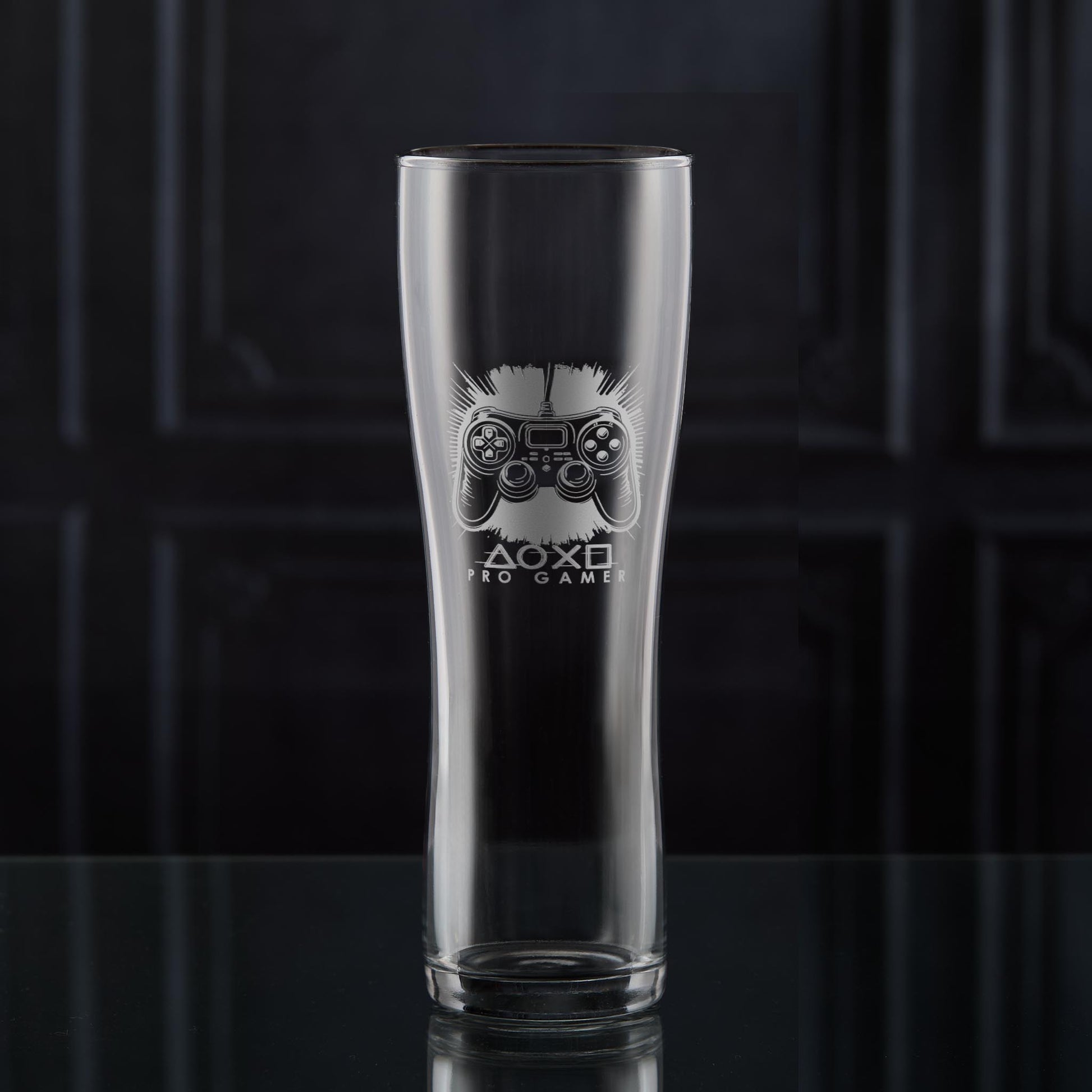 Pint glass with engraved games controller design on a dark background