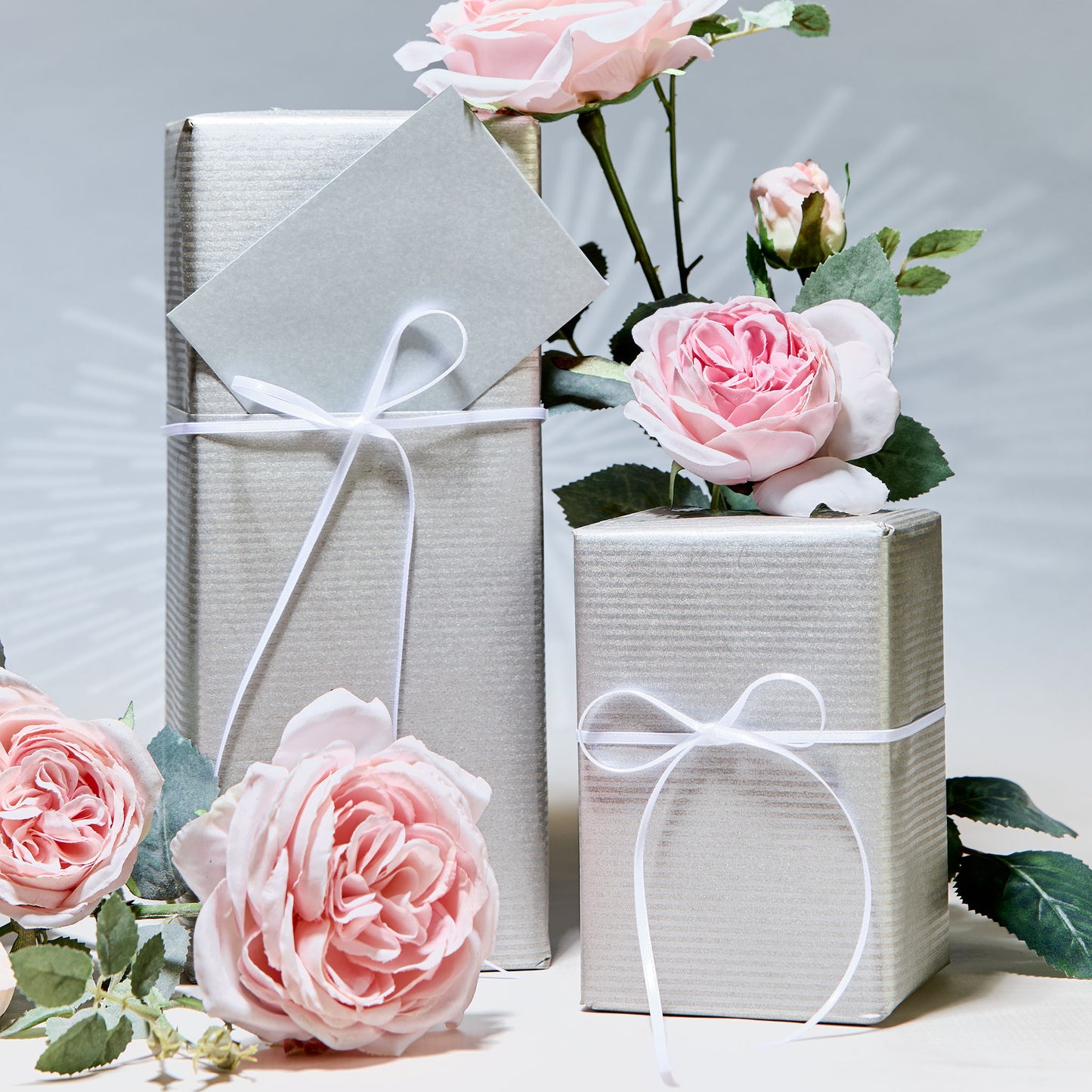 two boxes gift wrapped with silver paper and ribbons