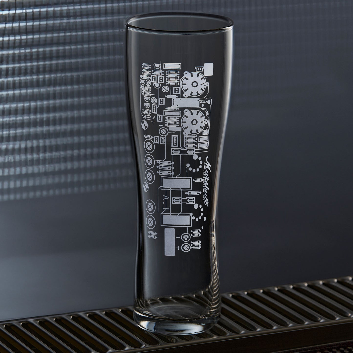 Guitar amp circuit pint glass on a blue background, showing pilsner shape and engraved detail.