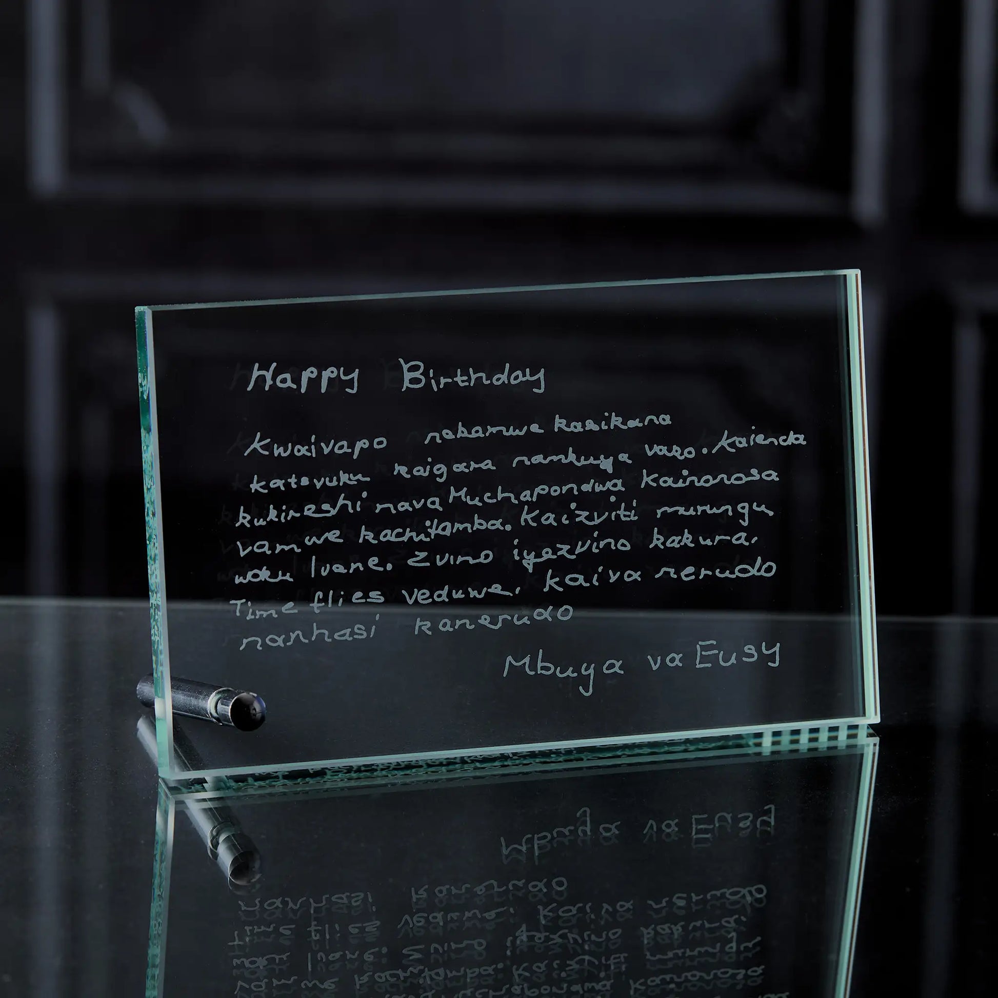 Glass plaque with engraved birthday message on a reflective surface