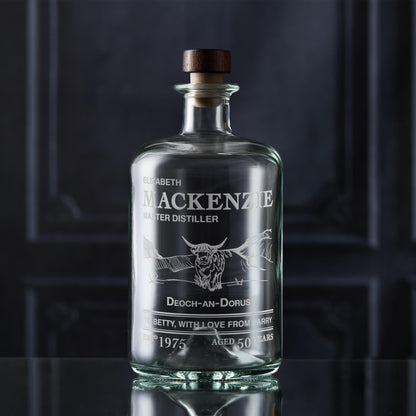 Glass decanter bottle engraved with a label featuring custom text and a Highland Coo 