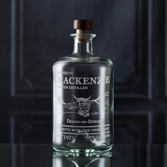 Glass decanter bottle engraved with a label featuring custom text and a Highland Coo 