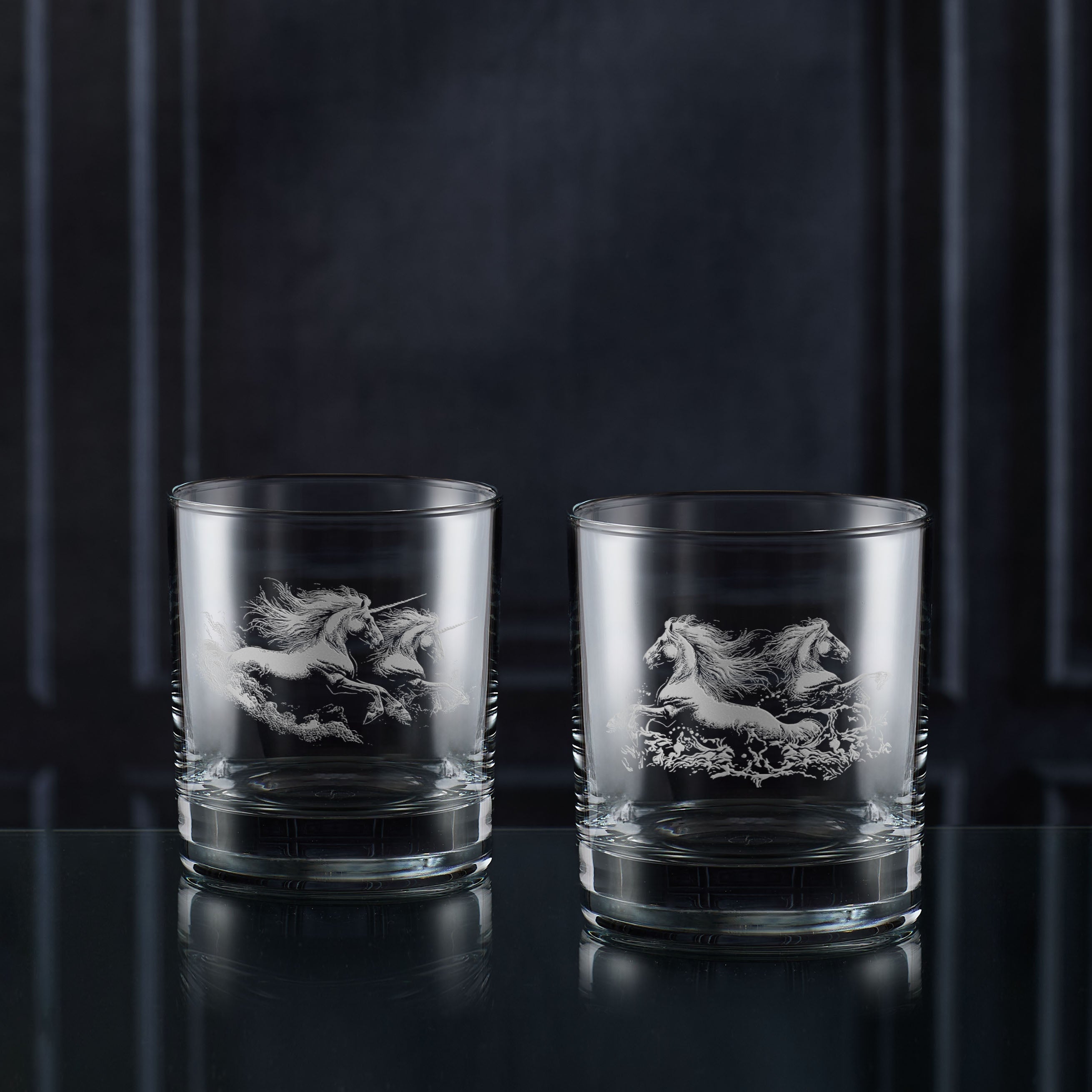 Two glass tumblers with engraved horse designs on a dark background