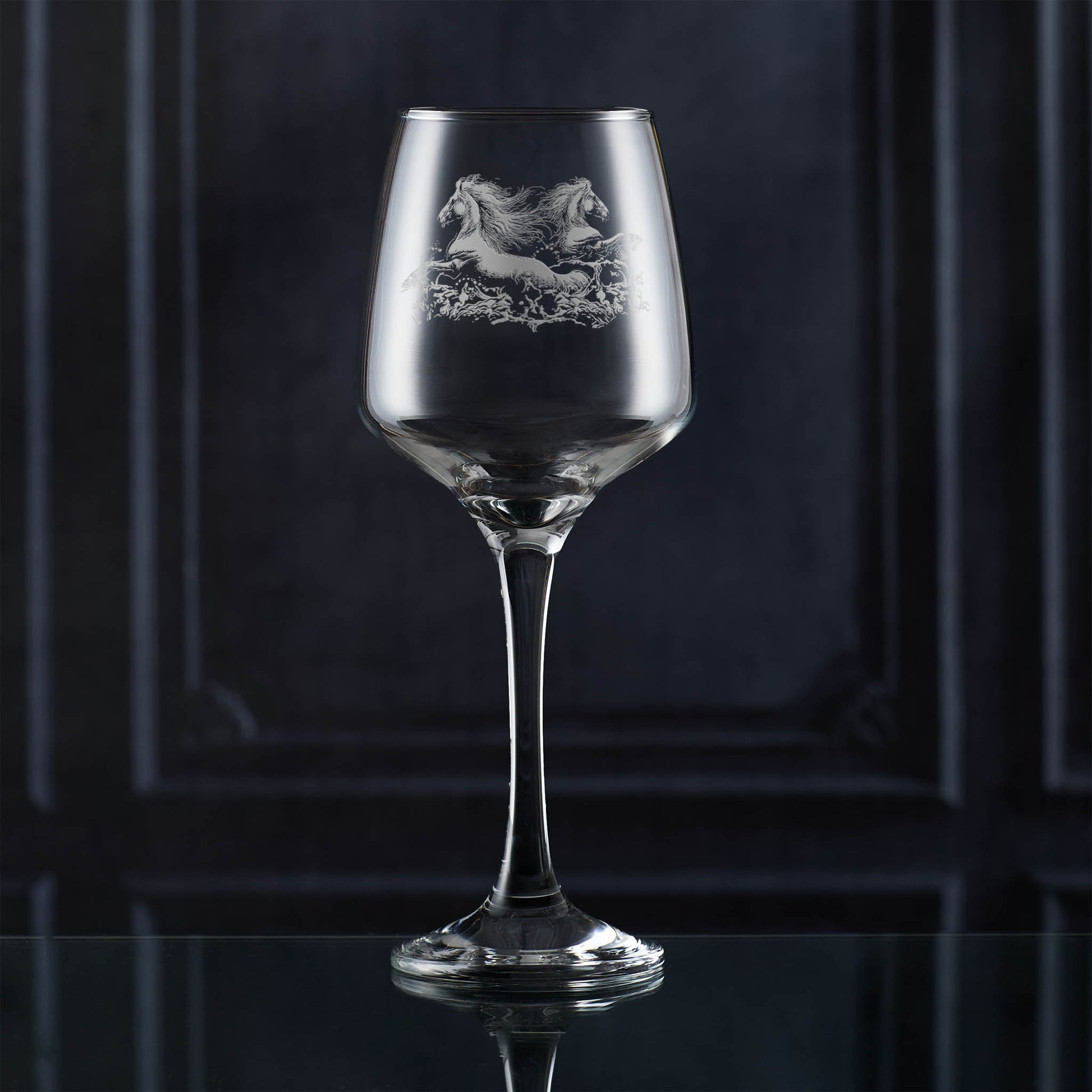 Wine glass with engraved horse design on a dark background