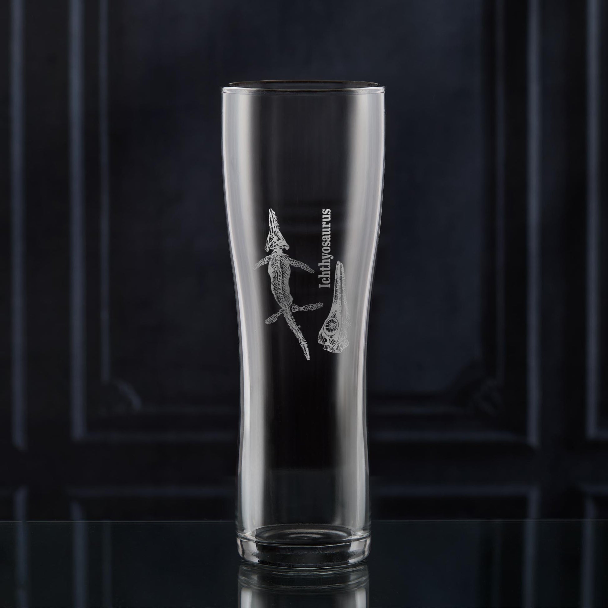 Pint glass with dinosaur fossil engraving on a dark background