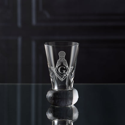 Firing glass engraved with Masonic paste master square and compass symbol on a black reflective surface