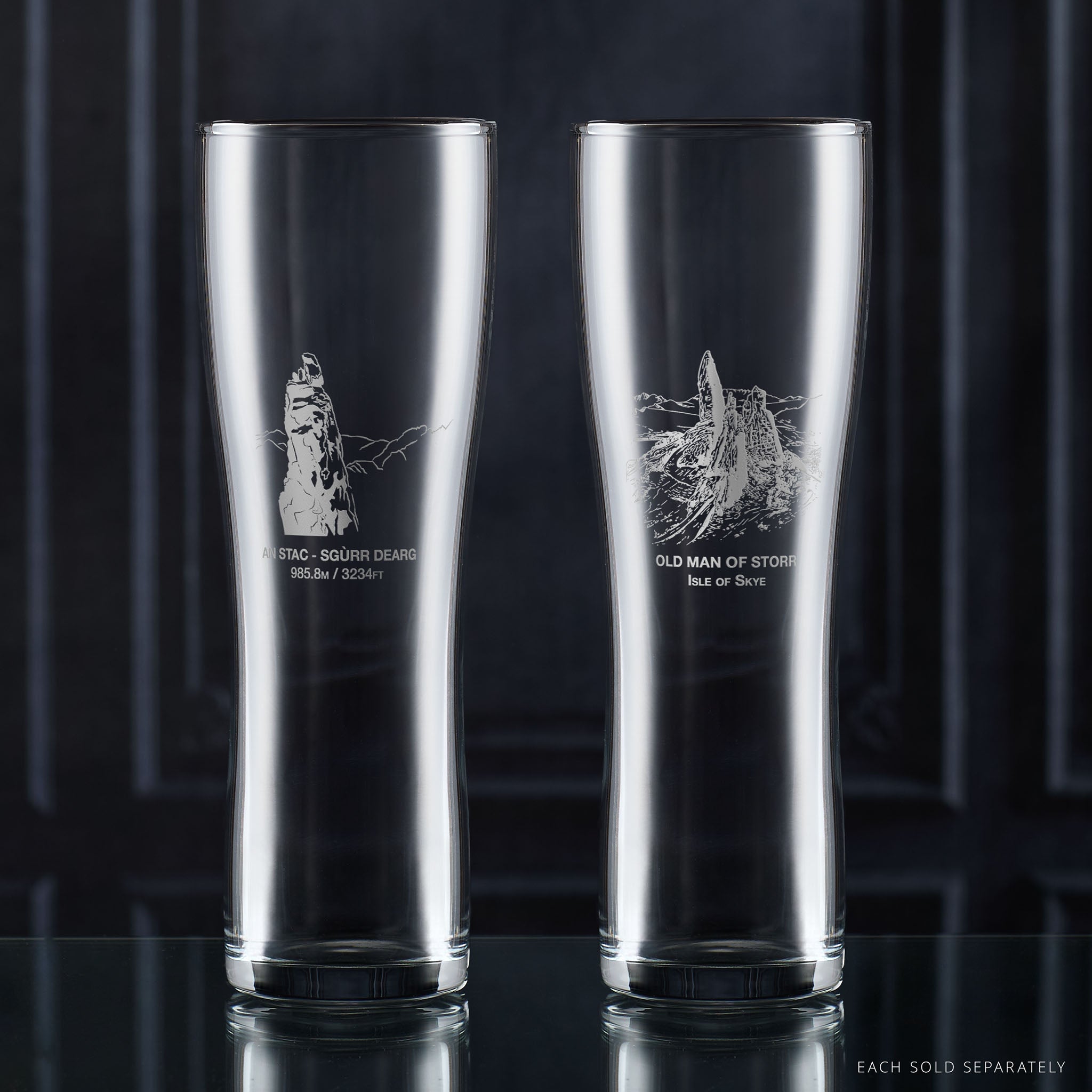 Two pint glasses with engraved Isle of Skye landscape designs on a dark background