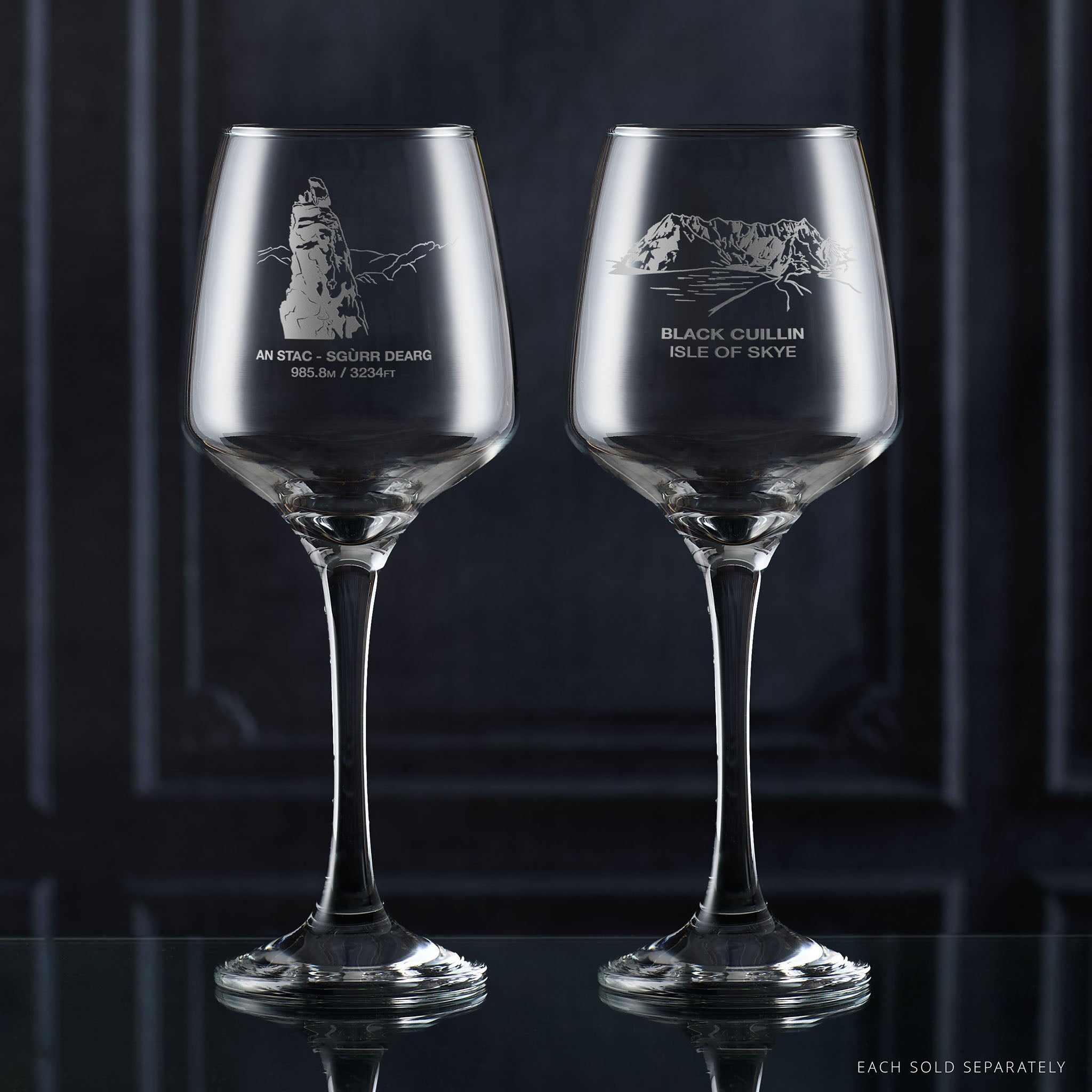 Pair of wine glasses with engraved mountain designs on a dark background