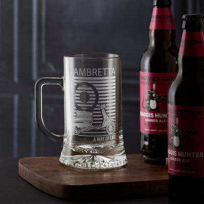 Tankard with engraved Lambretta GP design and text, placed on a wooden surface with two bottles of beer in the background.