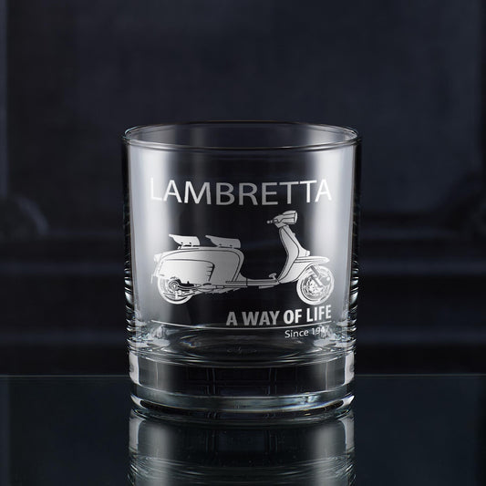 Clear glass whiskey tumbler with Lambretta scooter design and text on a dark background